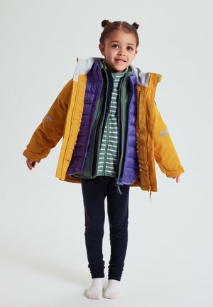 Colorful outerwear includes a yellow parka with reflective accents, a purple puffer, and a green and striped top, worn over navy leggings.