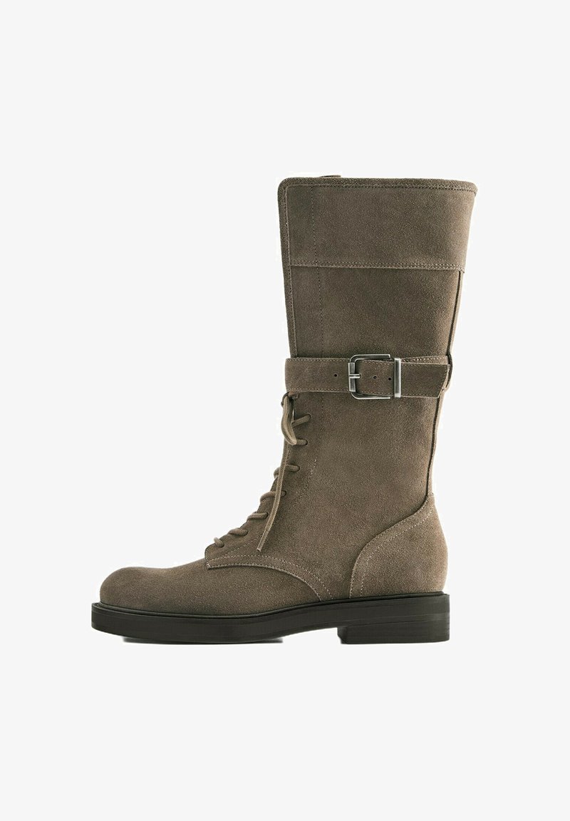 Botte en suède marron mi-mollet avec laçage à l'avant, bride à boucle argentée autour de la cheville, talon et semelle noirs et bas.