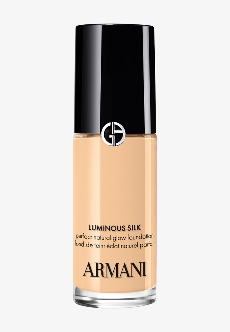 Bouteille de fond de teint Armani Luminous Silk avec bouchon noir, liquide beige à l'intérieur, et logo sur un flacon en verre transparent.