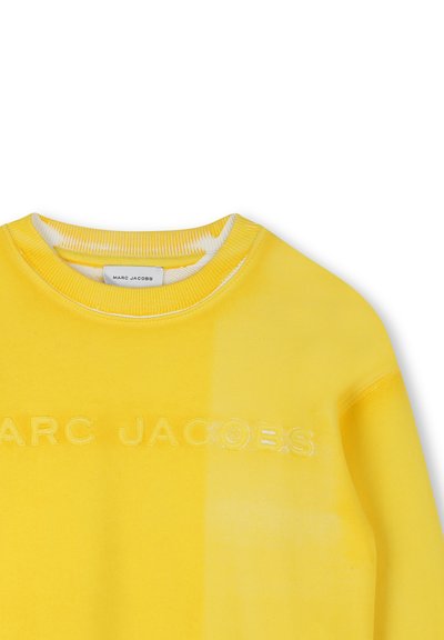 Felpa gialla realizzata in tessuto morbido, con scollatura a girocollo, logo "MARC JACOBS" in rilievo e effetto sfumato.