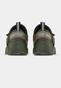 Ζευγάρι ελαιόχρωμων και καφέ αθλητικών παπουτσιών με ανακλαστικές ρίγες στην πλάτη και θηλιές, εμφανιζόμενο από πίσω σε λευκό φόντο.