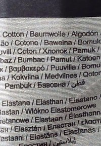 Etikett mit Angaben zur Stoffzusammensetzung, einschließlich "Baumwolle", "Elastan" und verschiedenen Übersetzungen in mehreren Sprachen. Weißer Hintergrund, schwarzer Text.
