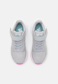 Une paire de chaussures de sport Adidas grises avec des sangles Velcro, des semelles intérieures bleu clair et des accents roses, vues de dessus sur fond blanc.