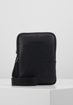 Kompaktowa czarna skórzana torba listonoszka z przednią kieszenią, zamkiem błyskawicznym i regulowanym, materiałowym paskiem na białym tle.