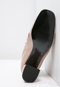 Nude lädersko med låg klack, med en slät yta och en ruggad svart gummisula. Designen är minimalisk och str ömlinjeformad.