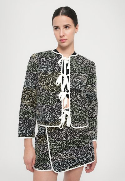 Jachetă din material negru cu un model pătat multicolor, închidere frontală cu șnur, margine contrastantă albă. Asortată cu o fustă mini corespunzătoare.