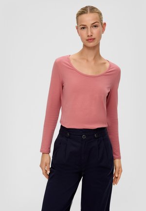 Langemouwige top met een scoopneck in een zachte roze stof, gecombineerd met hooggeritage marineblauwe broek met twee knopen en geplooide details aan de voorkant.