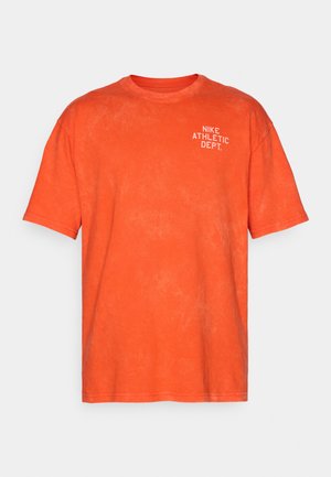 Orange cotton t-shirt with a relaxed fit, featuring a white "NIKE ATHLETIC DEPT." print on the upper left side. Soft texture.