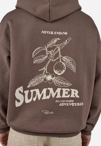 Brun hættetrøje med et grafisk print af blade og frugt på ryggen, med teksten "SOMMER FYLDT MED EVENTYR" i hvid.