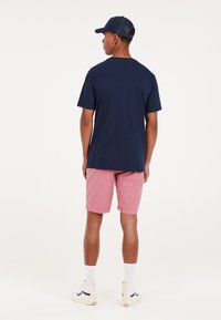 Camiseta de algodón navy, pantalones cortos rosa, calcetines blancos y zapatillas blancas. Ajuste casual, diseño simple y pantalones cortos hasta la rodilla con una textura suave.