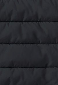 Tela de chaqueta acolchada negra con una textura suave, que presenta líneas de acolchado horizontales y un ligero brillo, que indica aislamiento y calidez.