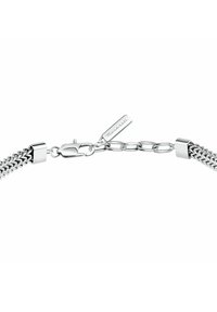 Bracciale in argento con design intrecciato, chiusura a moschettone e un piccolo tag con il nome del marchio. Finitura metallica liscia e riflettente.