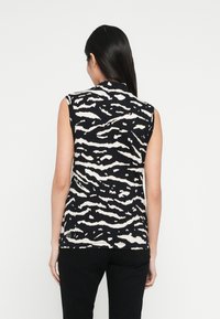 Fekete-fehér ujjatlan felső zebramintával. Puha anyagból készült, magas nyakkal és laza szabással.