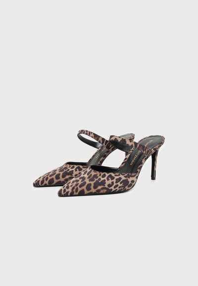 Ζευγάρι pointed-toe mules με τακούνι και μοτίβο λεοπάρδαλης, με ένα λουράκι στο πάνω μέρος, σε απλό φωτεινό φόντο.