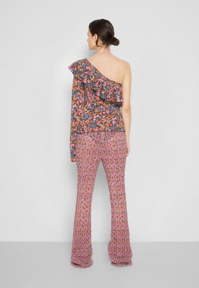 Top floral de um ombro só com detalhe em babados em fundo escuro; combinado com calças flare texturizadas em rosa com um padrão floral misto.