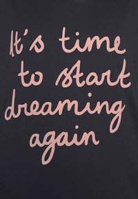 Czarna bawełnana koszulka w luźnym kroju z różowym pisanym tekstem, który brzmi: "Czas znów zacząć marzyć."