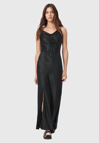 Abito maxi in satin nero con scollo a V, parte anteriore arricciata e spacco laterale. La texture liscia e la silhouette aderente esaltano il suo design elegante.
