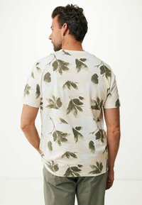 Kortärmad, ljusfärgad t-shirt av mjukt tyg, med ett grönt lövmönster över ryggen. Rundhalsad design.