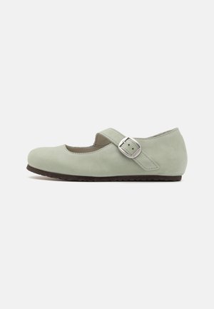 Zapato plano Mary Jane de ante verde claro con puntera redonda, una suela oscura de contraste y una cinta lateral con detalle de hebilla plateada.