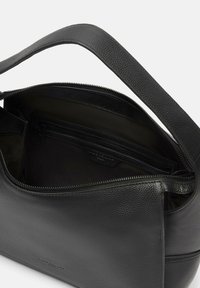 Sac à main en cuir noir avec une finition texturée, doté d'un compartiment principal zippé et d'une petite poche intérieure. Bandoulière réglable.