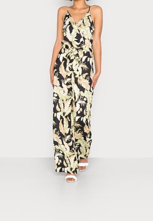 Floral jumpsuit featuring a black background with green and peach leaves, slim straps, a v-neckline, and a tied waist.