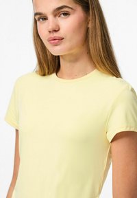 Geel T-shirt met korte mouwen en een ronde halslijn, met een gladde textuur en een aansluitend ontwerp. De stof lijkt lichtgewicht en zacht te zijn.