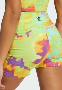 Färggranna tie-dye shorts med en blandning av grönt, gult, rosa och lila. Tillverkade av mjukt tyg med en svart logotyp på midjebandet.