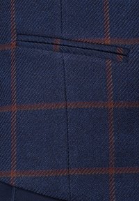 Tkanina w granatowym wzorze z subtelną teksturą w rybią ość; zawiera kieszeń z br ązowymi akcentami w kratkę oraz starannie wykonane detale szwów.