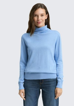 Hellblauer Rollkragenpullover aus weichem Strickmaterial, mit langen Ärmeln und taillierter Passform, kombiniert mit dunkelblauen Jeans.