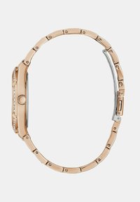 Rožno zlatna ura z verižnim zapestjem, pravokotno ohišje, jasni kristalni poudarki in sijoč srebrni zaponka. Gladka, sijoča kovinska tekstura.