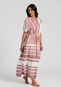 Maxiklänning med vit bas och röda geometriska mönster, korta ärmar, midjeskärp och högslitsar i fållen.