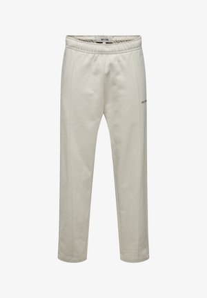 Pantalons de jogging beige clair fabriqués en tissu doux, dotés d'une taille élastique, de coutures latérales et d'un petit logo noir sur la cuisse.
