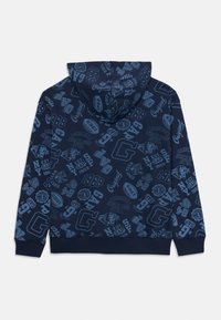 Felpa blu navy con stampe grafiche azzurro chiaro su tutta la superficie, tra cui "GAP," "1969," teste di tigre e loghi a tema sportivo.