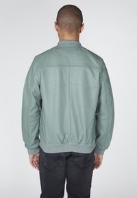 Zelená kožená bombera s žebrovanými manžetami a spodním lemem; hladká textura a minimální detaily šití, z pohledu zezadu.