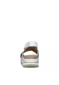 Sandalino bianco con cinturino in velcro, tacco aperto, imbottitura sulla soletta e suola sagomata. Texture liscia e design minimalista.