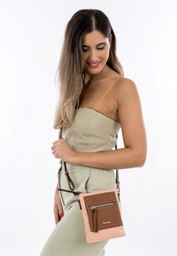 Crossbody taška v růžové a hnědé barvě, s texturovaným předním dílem z umělé kůže a zipovou kapsou, nastavitelným popruhem a kompaktním obdélníkovým tvarem.