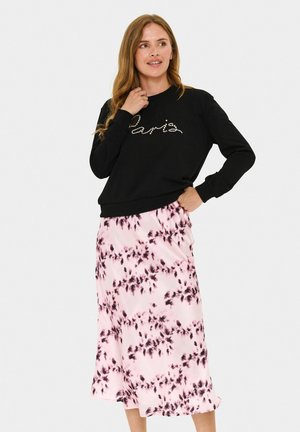 Schwarzer Sweatshirt mit "Paris" in Strass, kombiniert mit einem rosa Batik-Midikleid mit schwarzen Blumenmustern. Schmeichelnde Textur.