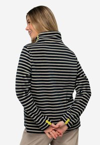 Pull en polaire avec des rayures bleu marine et crème, col élevé et accents jaune vif aux poignets. Texture douce et design décontracté.