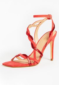 Rode hoge hak sandaal met een spitse neus, gemaakt van suède, met een verstelbare enkelband en gedraaide banden. Gladde textuur met glanzende accenten.
