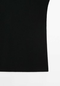 Gros plan sur un haut noir sans manches en tricot avec une texture simple et lisse sur fond blanc.