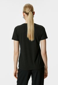 Camiseta negra de manga corta con cuello redondo, fabricada en un tejido suave y de corte recto. Diseño liso sin patrones visibles ni marcas.