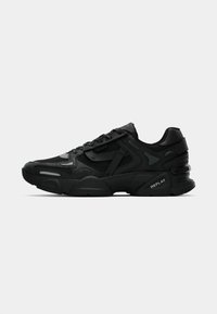 Black athletic sneakers with textured upper, reflective accents, and cushioned soles. Features laces and brand logo on the side.