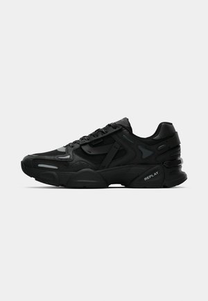 Black athletic sneakers with textured upper, reflective accents, and cushioned soles. Features laces and brand logo on the side.