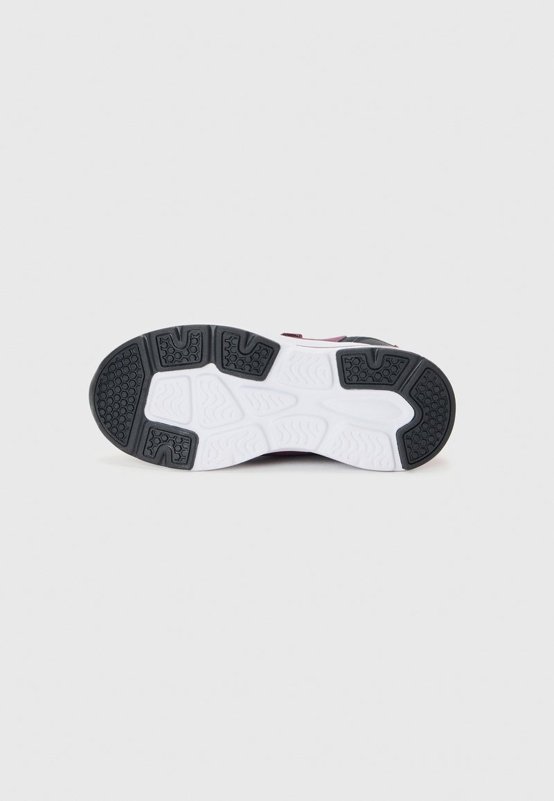 Suola di scarpa sportiva in bianco e nero con motivi di grip testurizzati, realizzata in un materiale gommoso resistente e con un design del battistrada intricato.