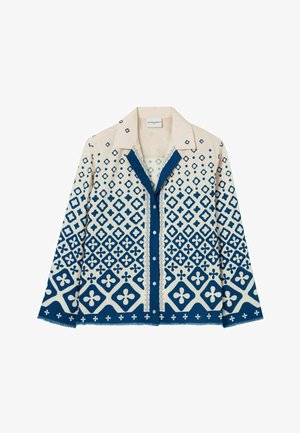 Camisa de botones con una base en color crema y patrones geométricos azules, incluyendo diamantes y motivos florales, y un cuello en contraste.