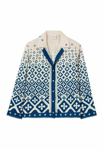 Camicia button-up con una base color crema decorata da motivi geometrici blu, tra cui diamanti e motivi floreali, e un colletto a contrasto.
