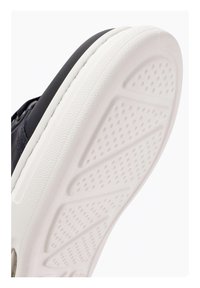 Suola di scarpa con una superficie in gomma bianca testurizzata, caratterizzata da un design del battistrada a motivi e un bordo superiore scuro circostante.