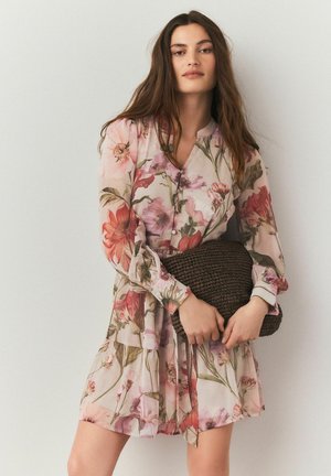 Blomstret kjole lavet af et blødt, let materiale med pink, rød og grønne mønstre. Den har en knappet front og lange, elastiske ærmer.