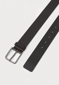Ceinture en cuir noir avec une finition texturée, boucle en métal argenté et accents de couture rouges. Présente plusieurs trous pour un ajustement réglable.