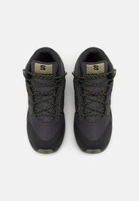 Czarne buty sportowe z fakturowaną siateczkową cholewką, neonowozielonymi sznurowadłami oraz wzmocnionym noskiem. Podeszwa odporna na poślizg. Logo na języku.